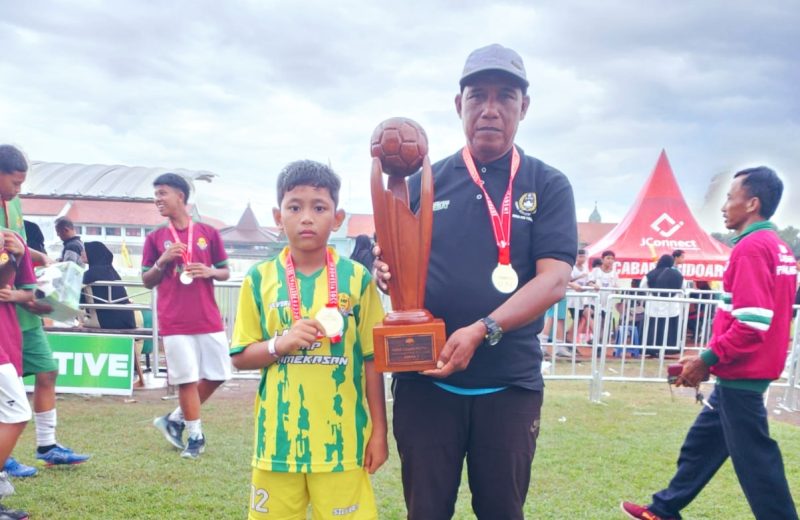 Kapten tim U 10, Rafa dan Pelatih SSB Laga Sota, Ach Zaini usai menerima penghargaan dalam turnamen Super Soccer Festival 2025 di stadion Jenggolo Sidoarjo, Minggu (6/7/2025).